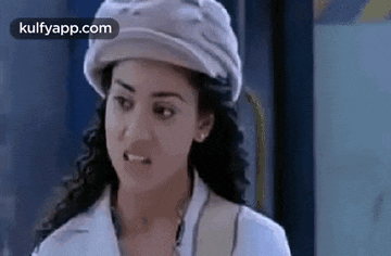 a woman wearing a hat and a white shirt is making a face .