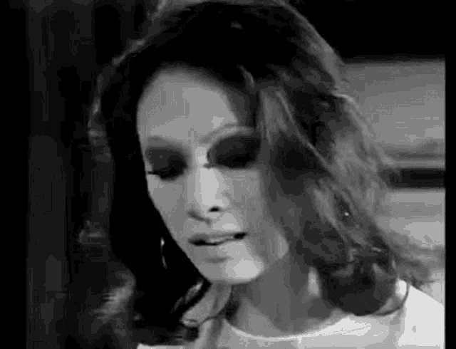 a black and white photo of a woman with long hair and earrings .