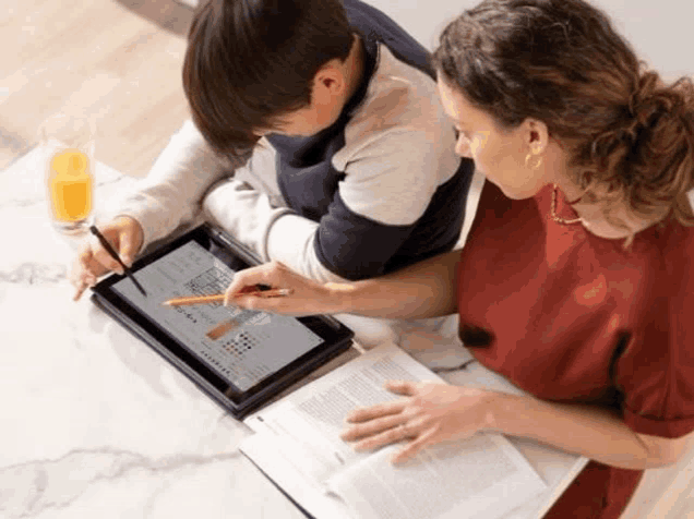 a woman and a child are looking at a tablet with a pencil