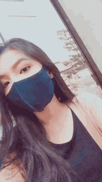 a woman wearing a blue face mask is taking a picture of herself