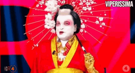 a man dressed as a geisha is holding an umbrella and smoking a cigarette .