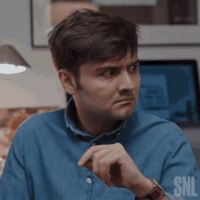a man wearing a denim shirt and a watch is making a funny face .