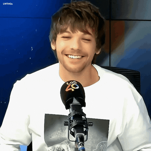 a man is smiling in front of a microphone that says los 40 on it