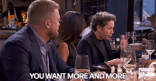 a group of people sitting at a table with the words " you want more and more " on the screen