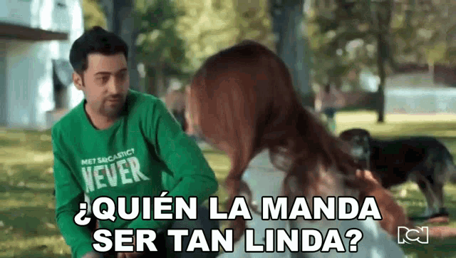 a man wearing a green shirt that says never is talking to a woman in a park