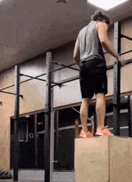 a man is standing on a box in a gym