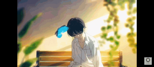 a boy is sitting on a wooden bench with his head down .