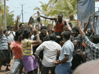 a man in an orange tank top is being lifted in the air by a crowd