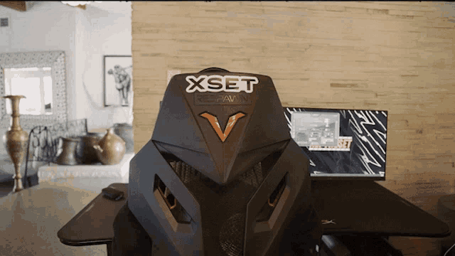 a black xset re-pawn chair sits on a desk in a living room