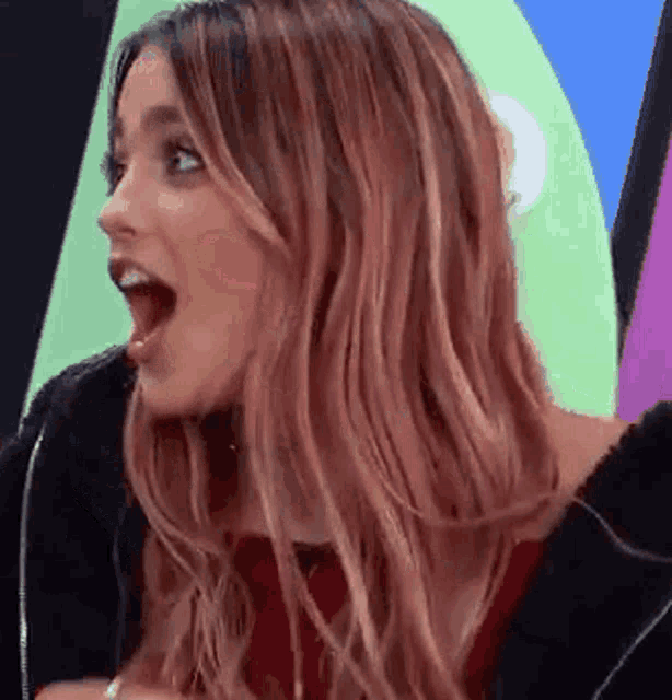 a woman with a surprised look on her face is wearing a black jacket .