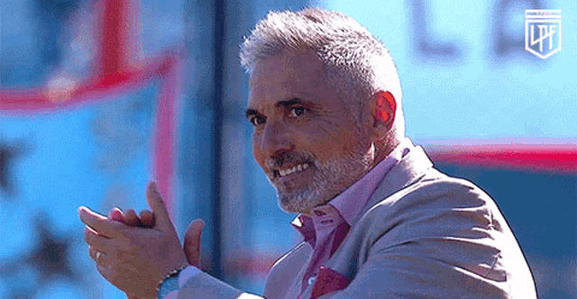 a man in a suit and pink shirt is clapping
