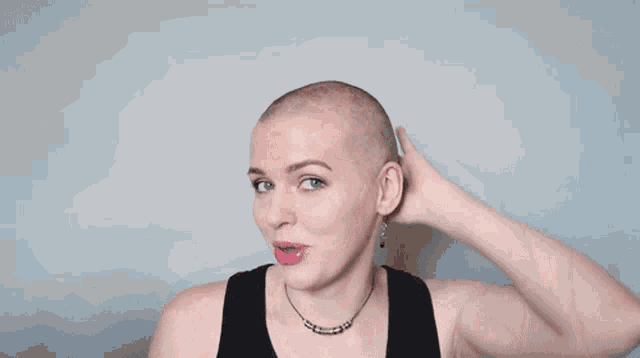 a woman with a shaved head is wearing a black tank top