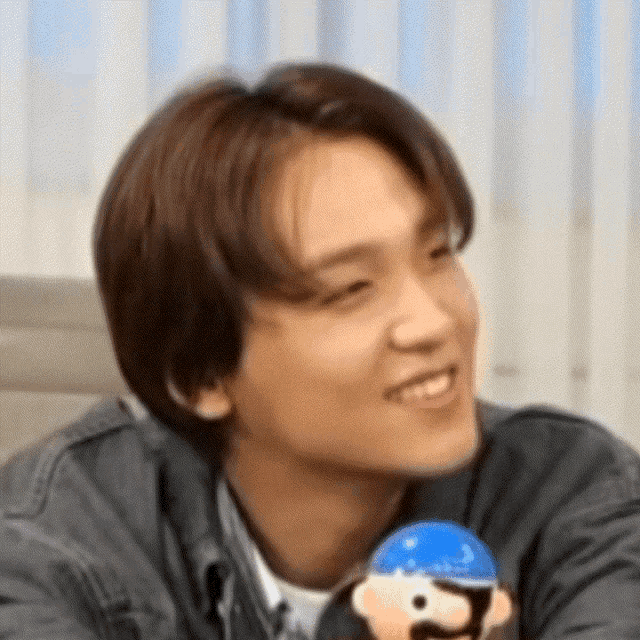 a young man is smiling while holding a stuffed animal .