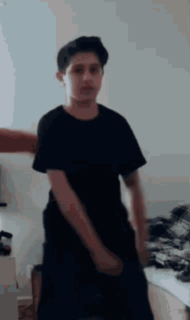 a young boy in a black shirt and black shorts is dancing in a room .