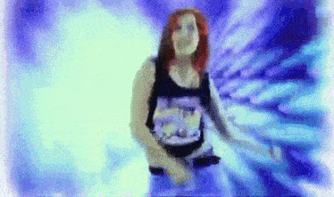 a woman with red hair is dancing in a dark room