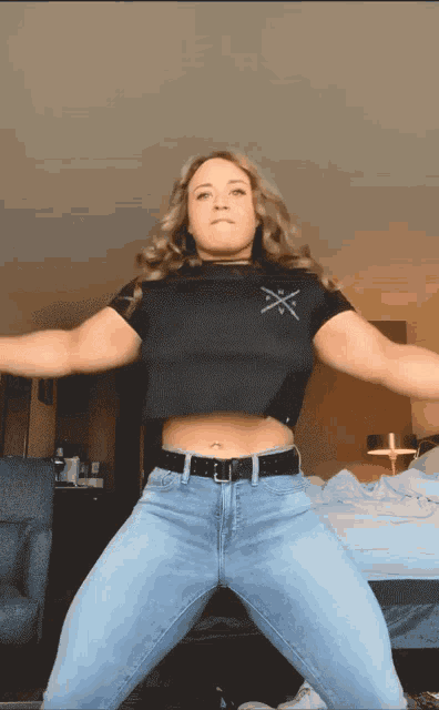 a woman wearing jeans and a black crop top with a cross on it