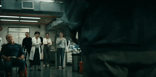 a group of people are standing in a room watching a man throw a lightning bolt .