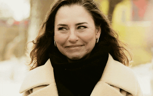 a woman wearing hoop earrings and a black scarf smiles