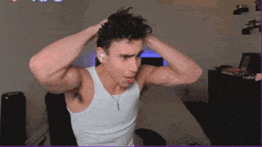 a man in a white tank top is sitting in a chair in a room .