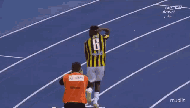 a soccer player wearing a number 8 jersey stands on a track