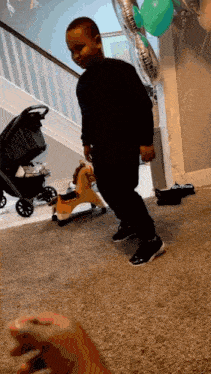 a little boy is standing in front of a rocking horse and balloons that say ' daddy ' on them