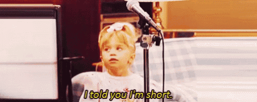 a little girl is standing in front of a microphone and says i told you i 'm short