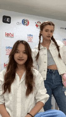 two girls are standing in front of a wall with logos for uoii and labi