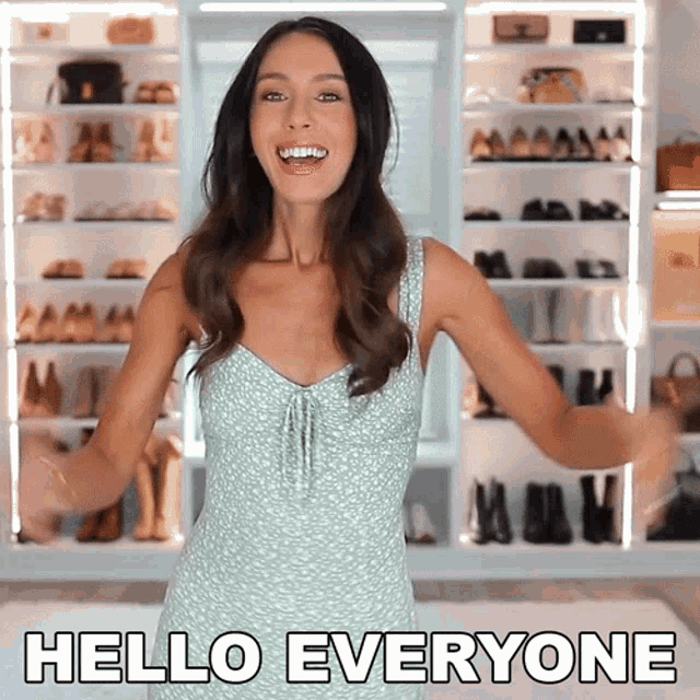 a woman in a green dress says hello everyone in front of a closet