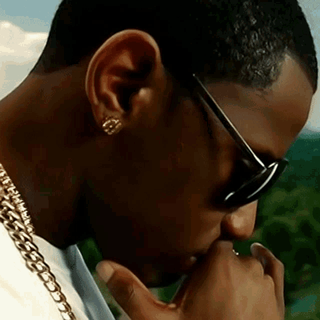 a close up of a man wearing sunglasses and chains