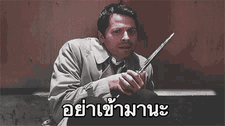 a man in a trench coat is holding a knife in his hand .
