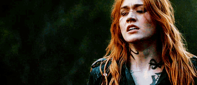a close up of a woman with red hair and a tattoo on her neck