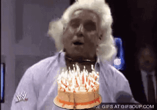 a man blowing out candles on a birthday cake with a w logo on his sleeve