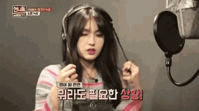 a woman wearing headphones is standing in front of a microphone and talking into it .