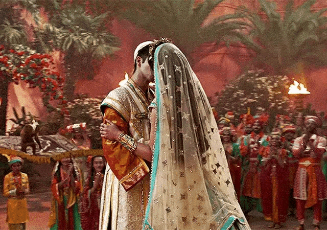 a man and woman are kissing in front of a crowd of people .