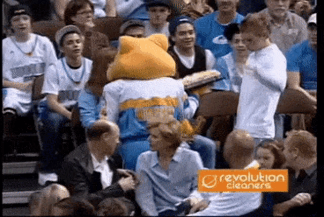a crowd of people watching a basketball game with a revolution cleaners advertisement