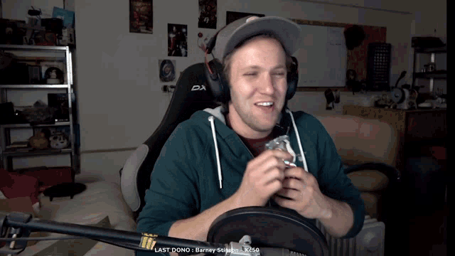 a man wearing headphones and a green sweatshirt is sitting in front of a microphone with the words last done on the bottom