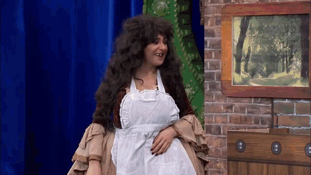 a woman in a wig and apron is standing in front of a picture of trees