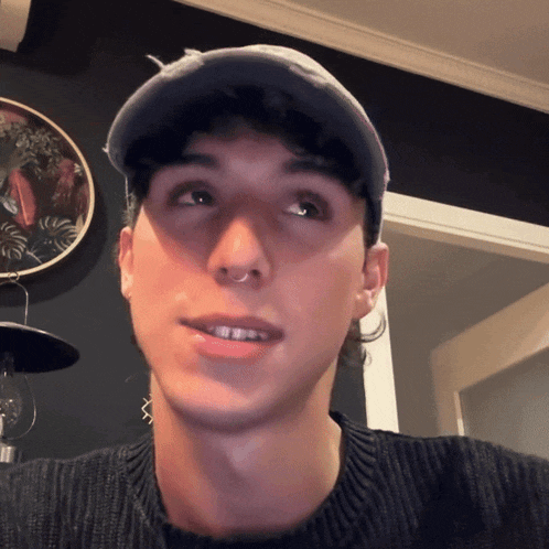a man wearing a hat and a sweater looks at the camera