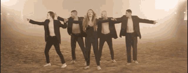 a group of people standing in a line with their arms outstretched pointing at something
