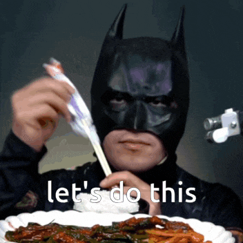 a man wearing a batman mask is eating with chopsticks