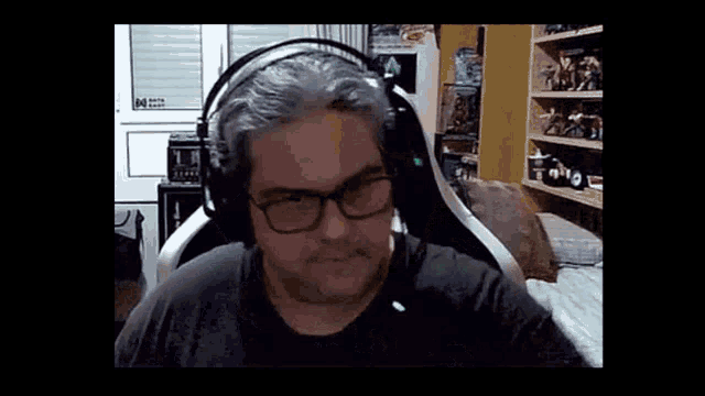 a man wearing headphones and glasses is sitting in a chair in a room .