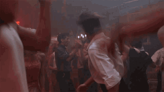 a man in a white shirt is dancing in a crowded room