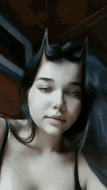 a woman with horns on her head is wearing a black bra .