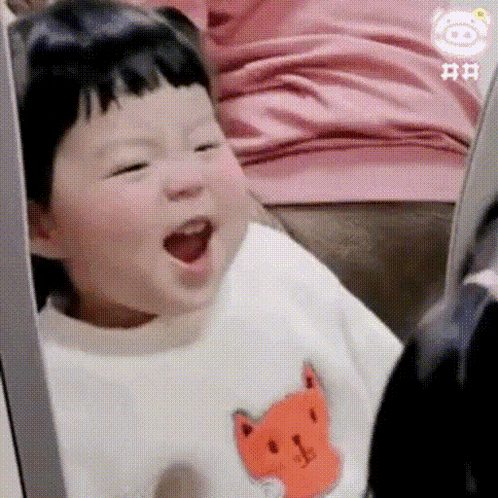 a baby is sitting on a couch with his mouth open and wearing a white sweater with a fox on it .