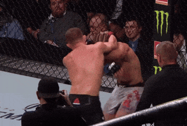 two men are fighting in a ring with a monster energy sign in the background