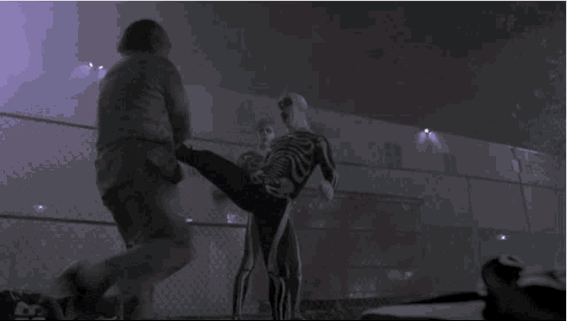 a man in a skeleton costume is kicking another man in the face