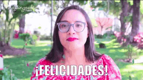 a woman wearing glasses says felicidades in a park
