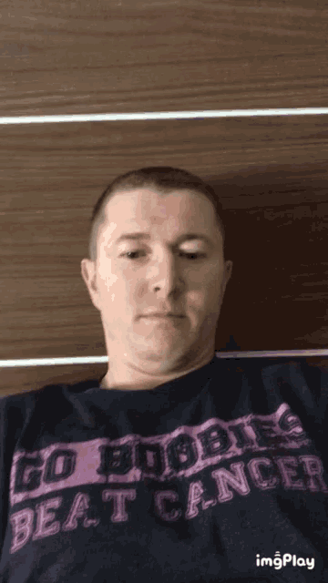 a man wearing a black shirt that says go boobies beat cancer