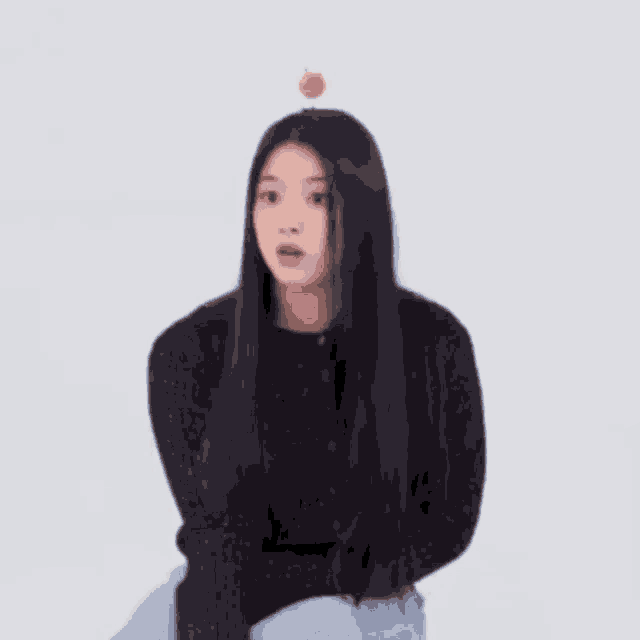 a young woman with long black hair is sitting on a chair with a donut on her head .