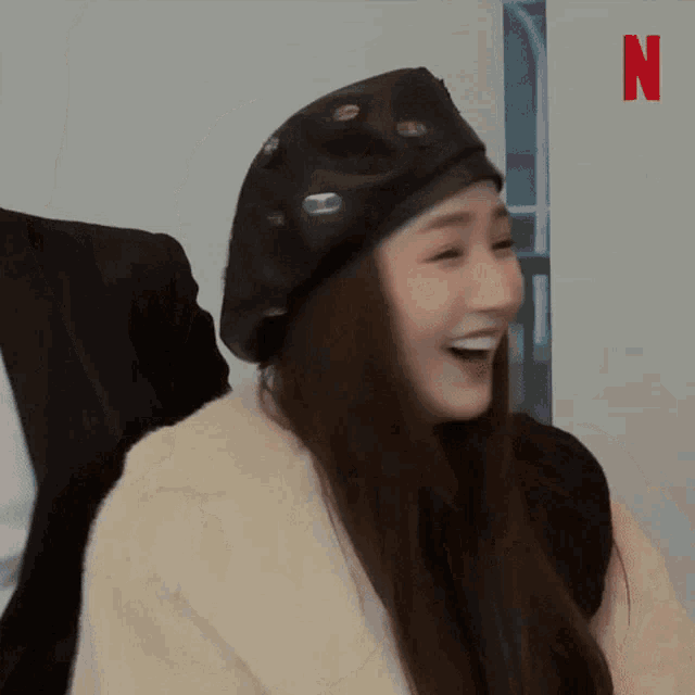 a woman wearing a beret and a fur coat is smiling while standing next to a man in a suit .
